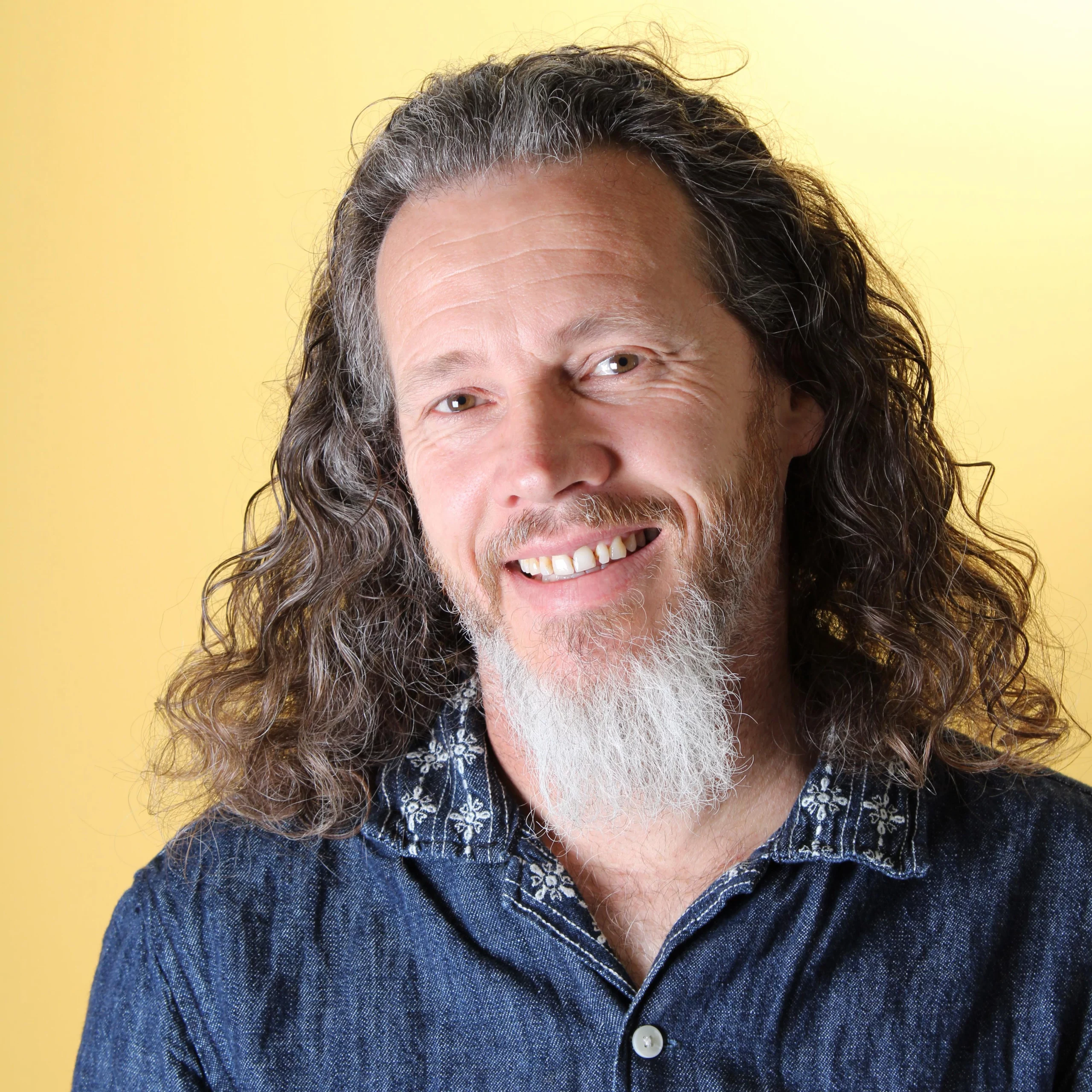 Portrait of Jason Piggott – sci-fi author and founder of Shadow Colony Media, smiling against a yellow background