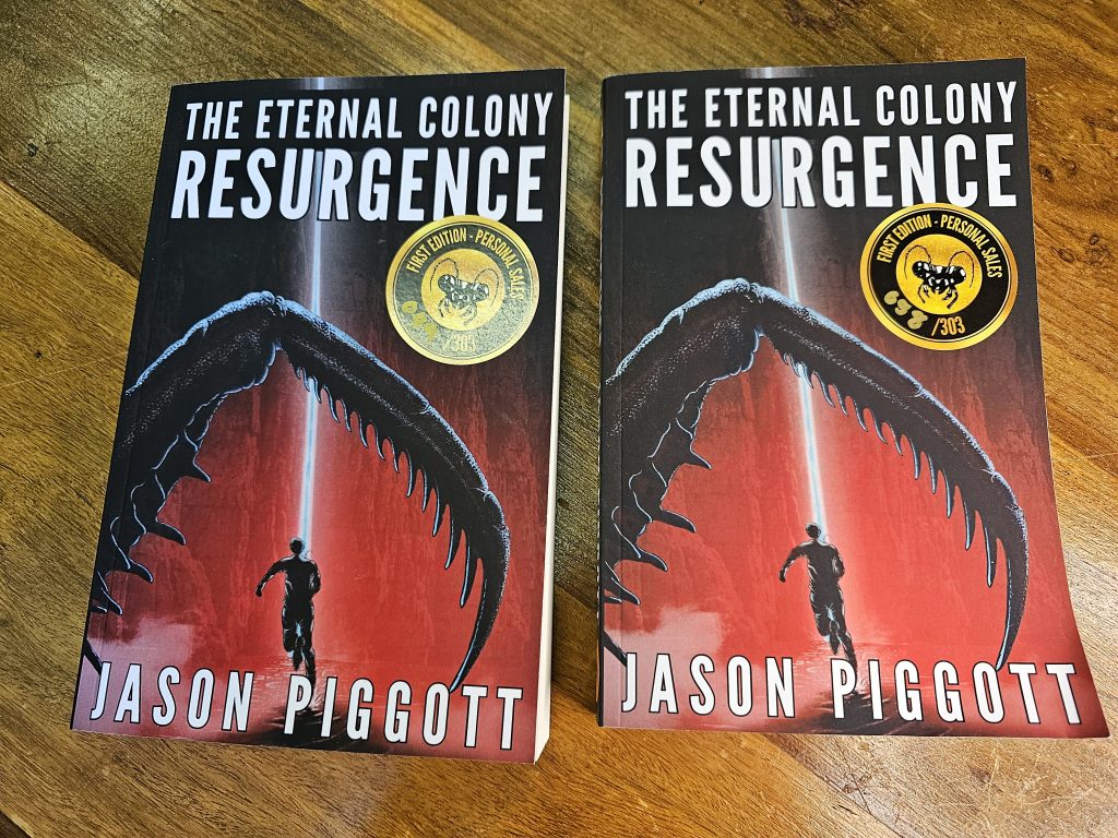 Two copies of Resurgence side-by-side on oak table