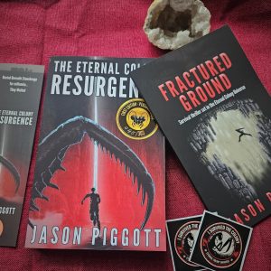 Resurgence & Fractured Ground books with bookmark and stickers on a red table cloth